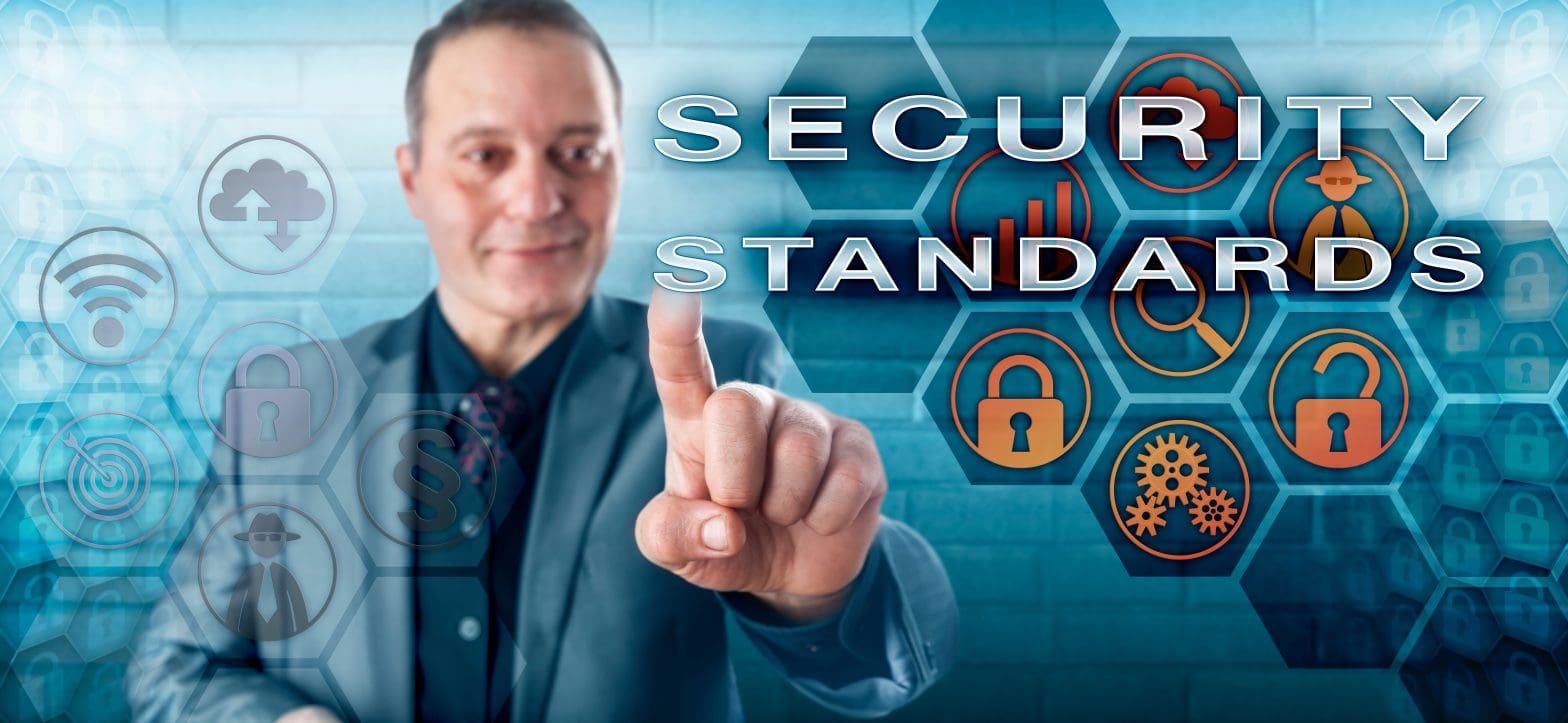 A smiling man touches a screen with words that say “Security Standards.”