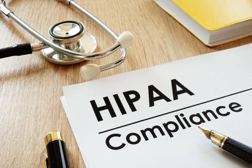 A pen resting on a piece of paper that reads, “HIPAA Compliance.”